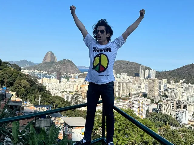Un homme pose, les bras levés, surplombant Rio de Janeiro.